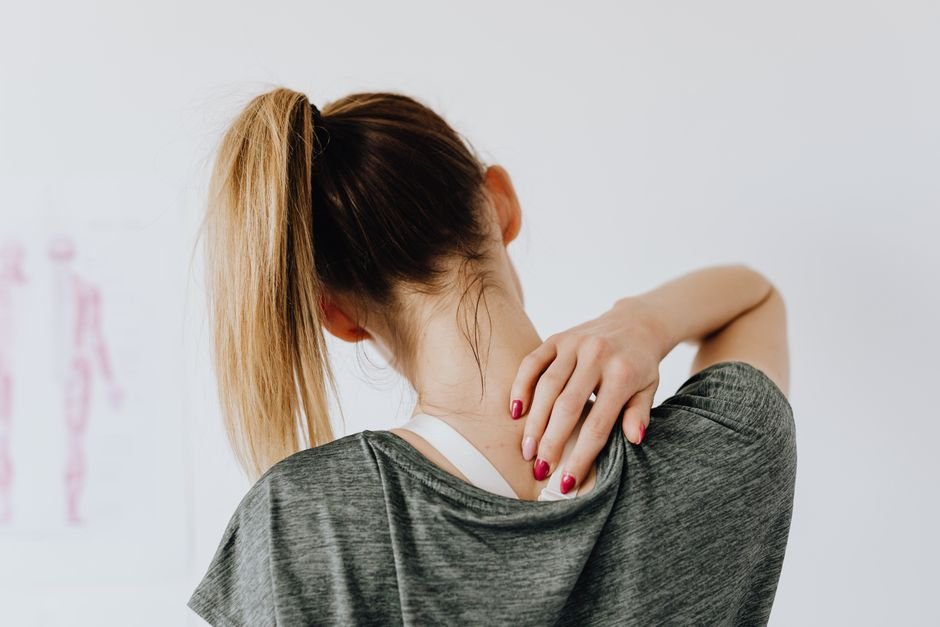 Woman holding her sore neck and shoulder, an area heat therapy can soothe