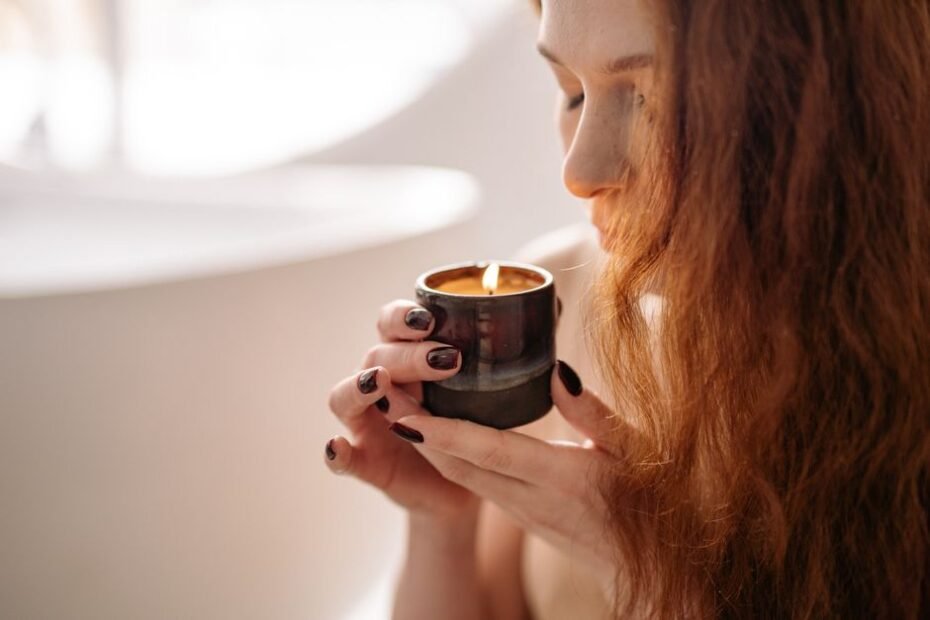 Woman relaxing while holding and smelling a lit scented candle