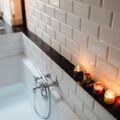 Relaxing bath with lit scented candles on the tub ledge