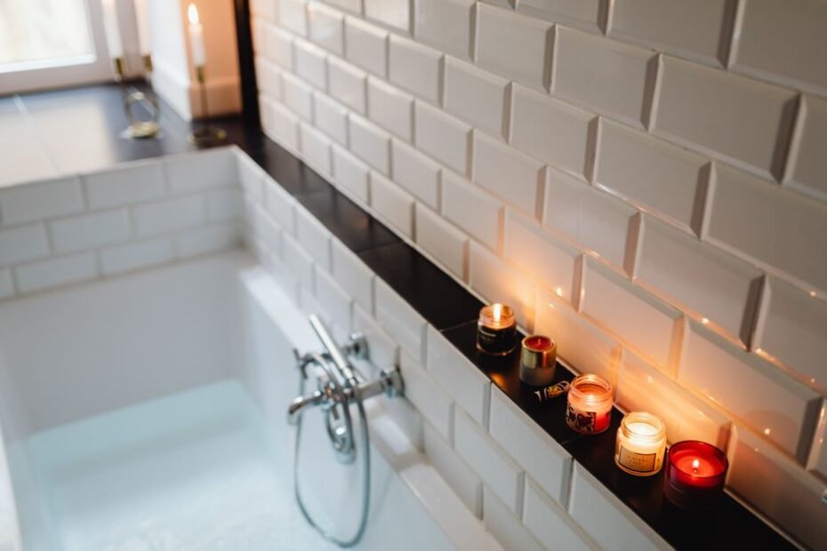 Relaxing bath with lit scented candles on the tub ledge