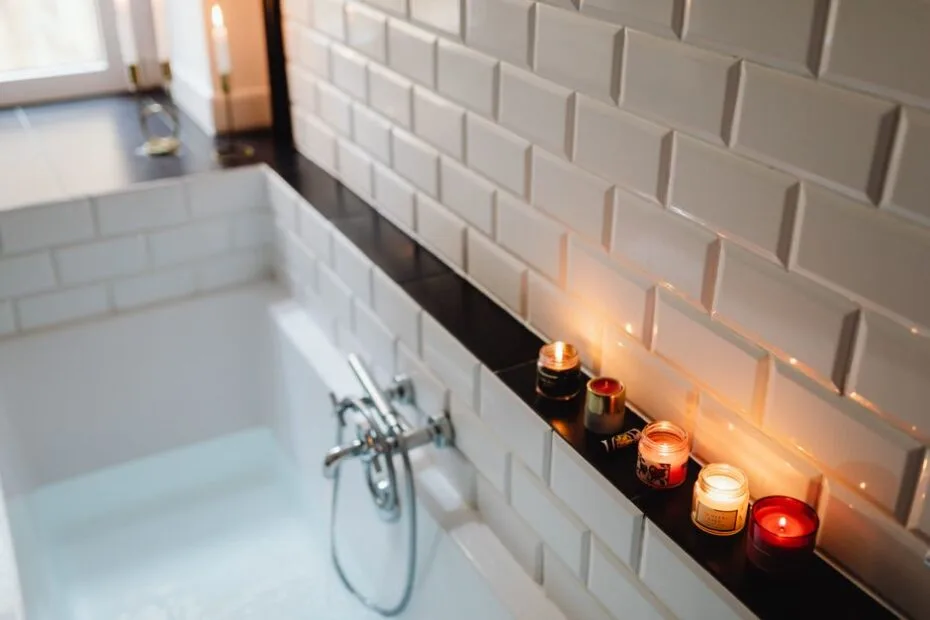 Relaxing bath with lit scented candles on the tub ledge