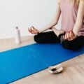 Woman sitting in a calm lotus pose on a yoga mat at home