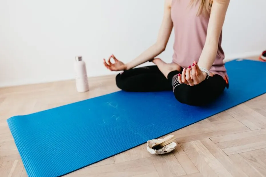 Woman sitting in a calm lotus pose on a yoga mat at home