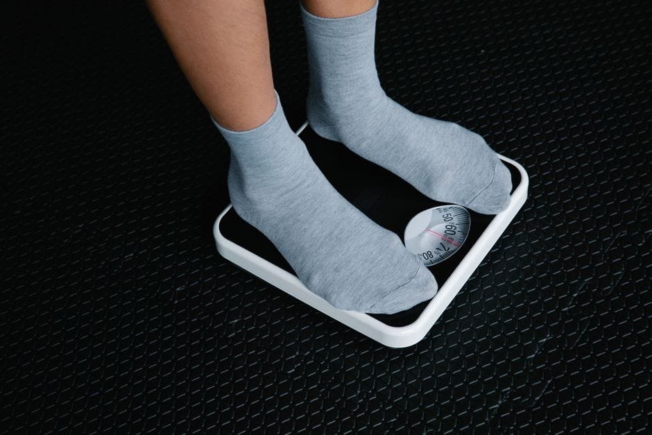 Feet in socks standing on a white bathroom scale