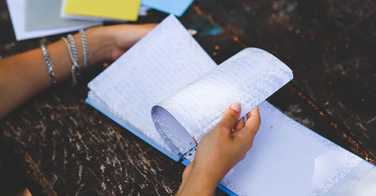 Hands writing notes in an open notebook