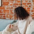 Woman wrapped in a cozy blanket on the couch, staying warm at home