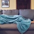 A woman napping under a blue blanket on a couch