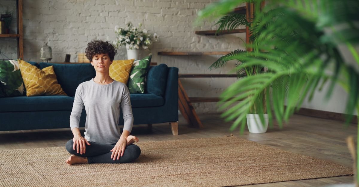 A person meditating cross-legged in a calm living room