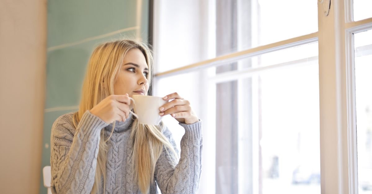 Woman drinking coffee peacefully at a window table