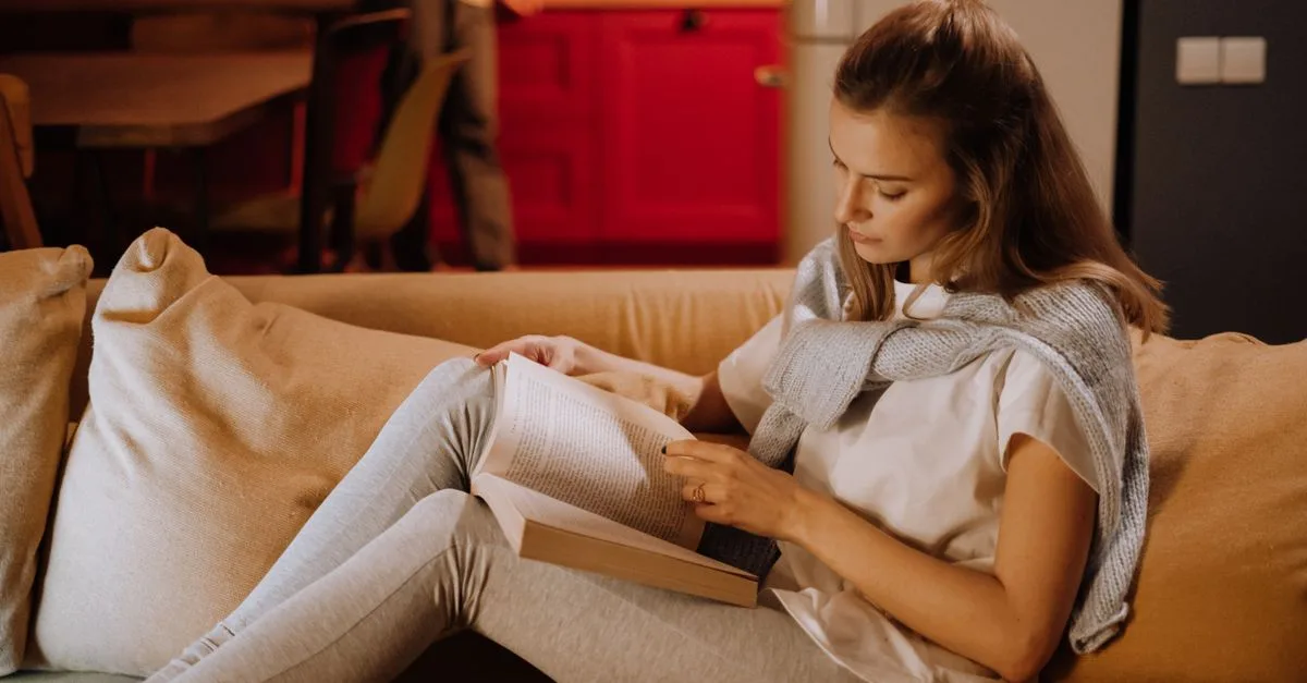Woman reading a book on the sofa instead of scrolling