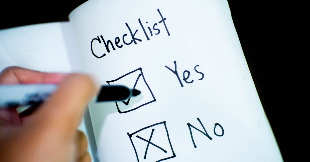 A hand marking a checklist in a notebook