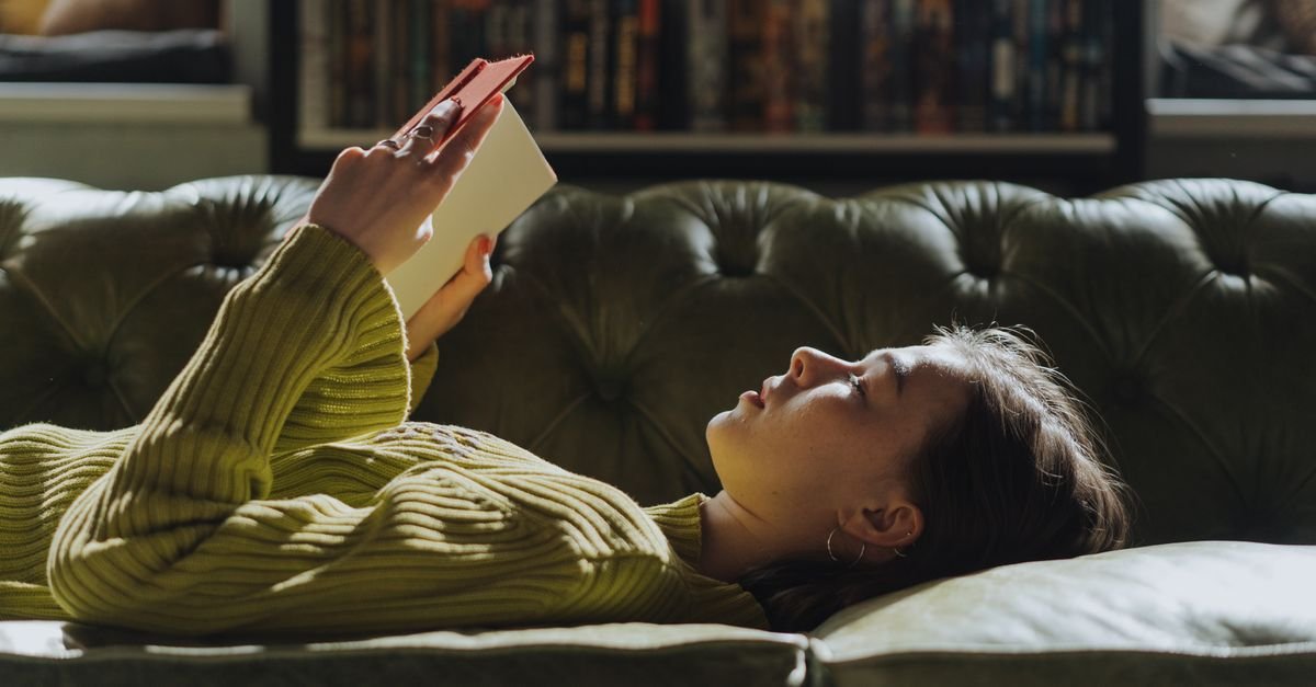 A woman lying on a couch reading a book