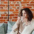 A woman wrapped in a blanket sipping tea on a restful day at home