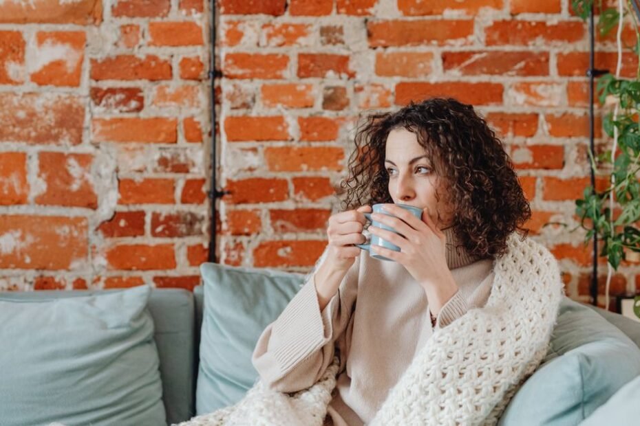 A woman wrapped in a blanket sipping tea on a restful day at home