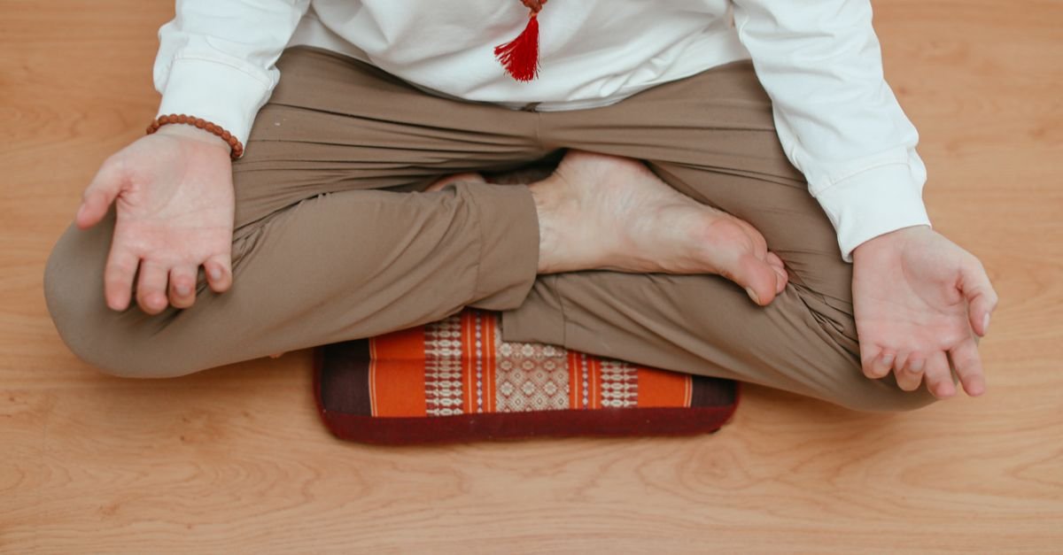 Person sitting cross-legged on a meditation cushion on the floor