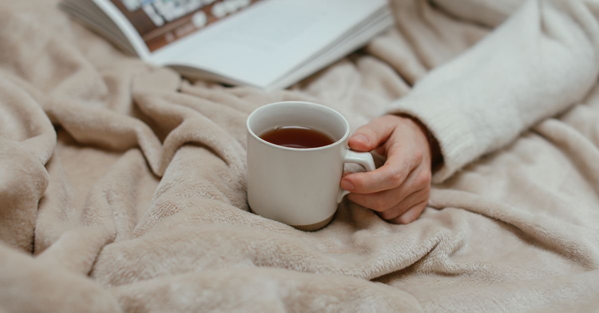 Woman wrapped up cosily with a warm cup of tea