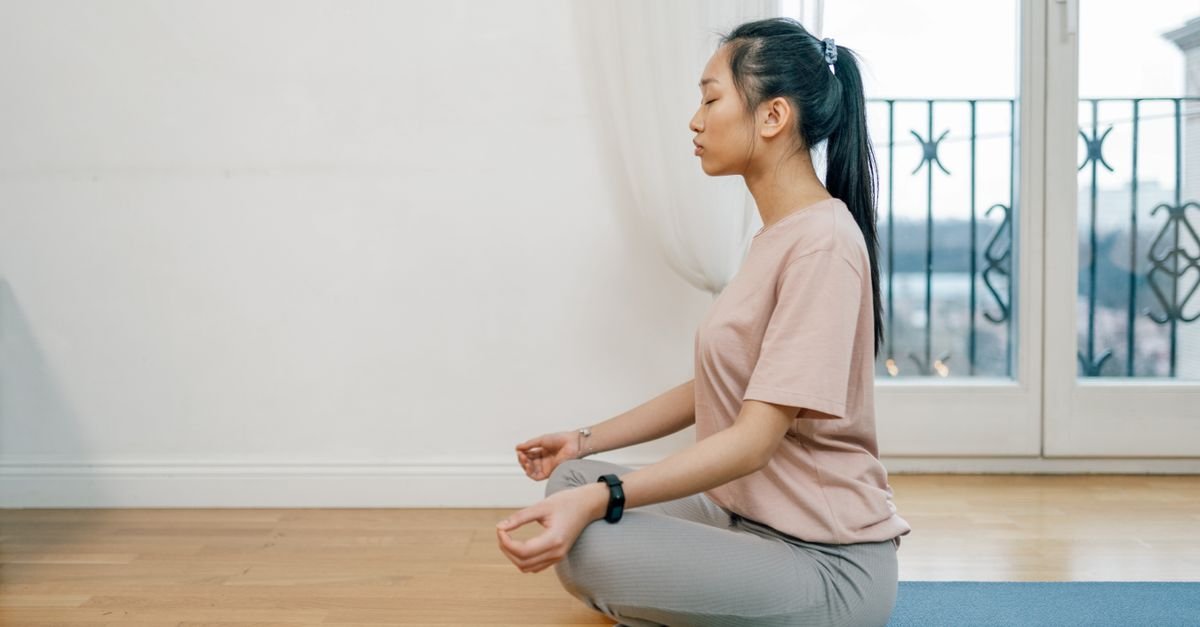 Woman sitting calmly in a meditation pose at home