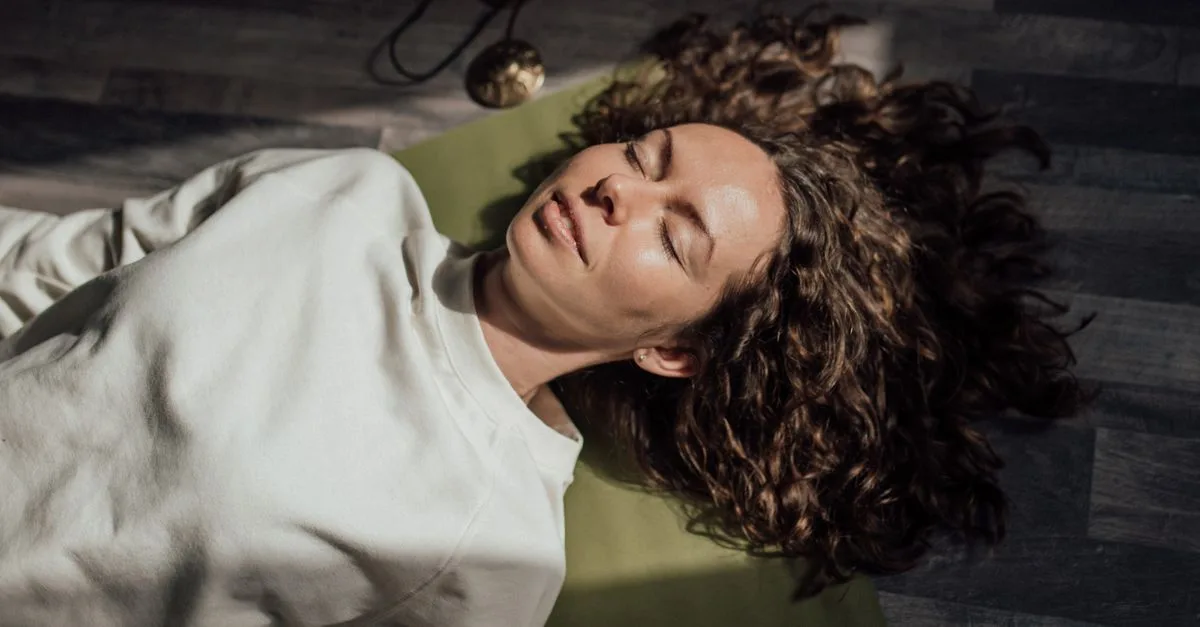 A woman lying down relaxed with eyes closed in soft light