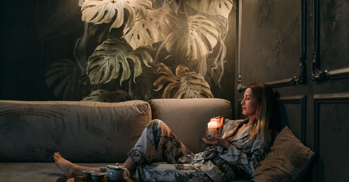 Woman unwinding on the sofa by candlelight in the evening
