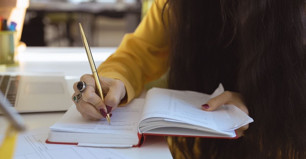 A woman writing in a planner at a desk
