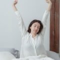 A woman stretching her arms happily while waking up in a bright bedroom