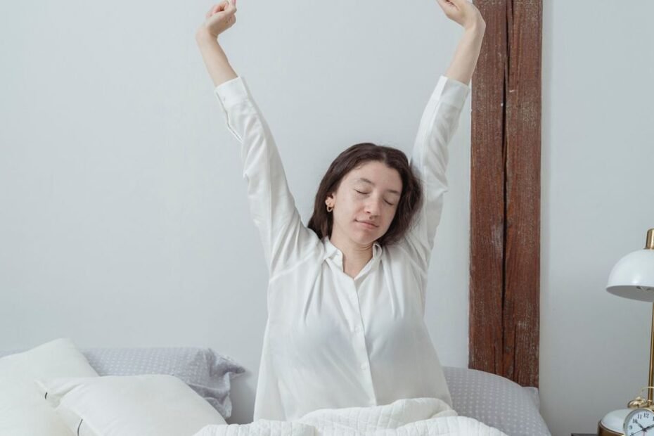 A woman stretching her arms happily while waking up in a bright bedroom