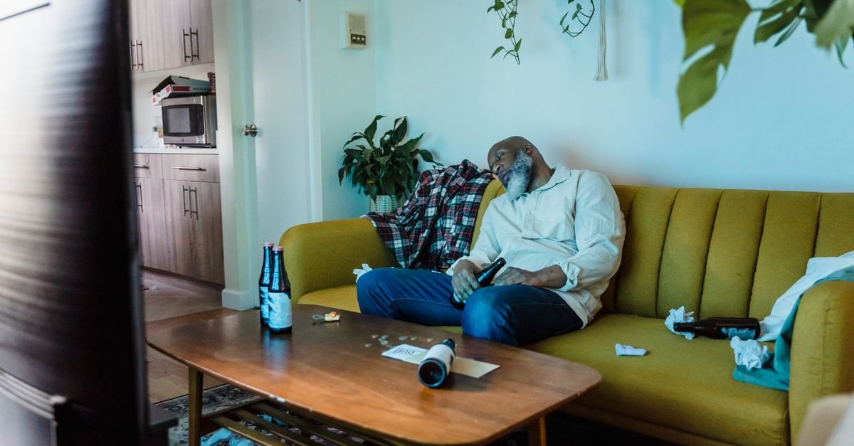 A man dozing on a yellow sofa in daylight