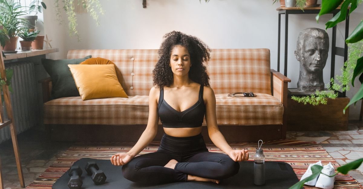 Woman meditating on a mat on the floor at home