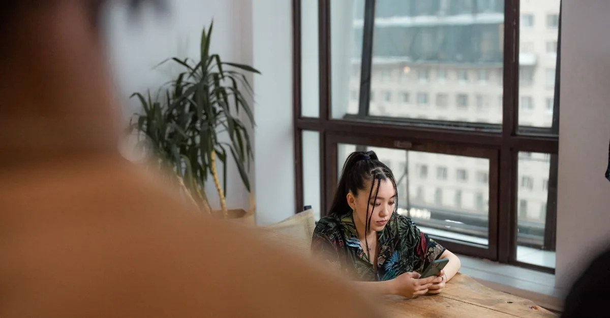 Woman at a table by the window, phone set aside