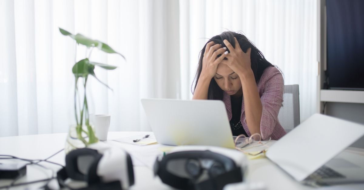 Overwhelmed woman holding her head in front of a laptop