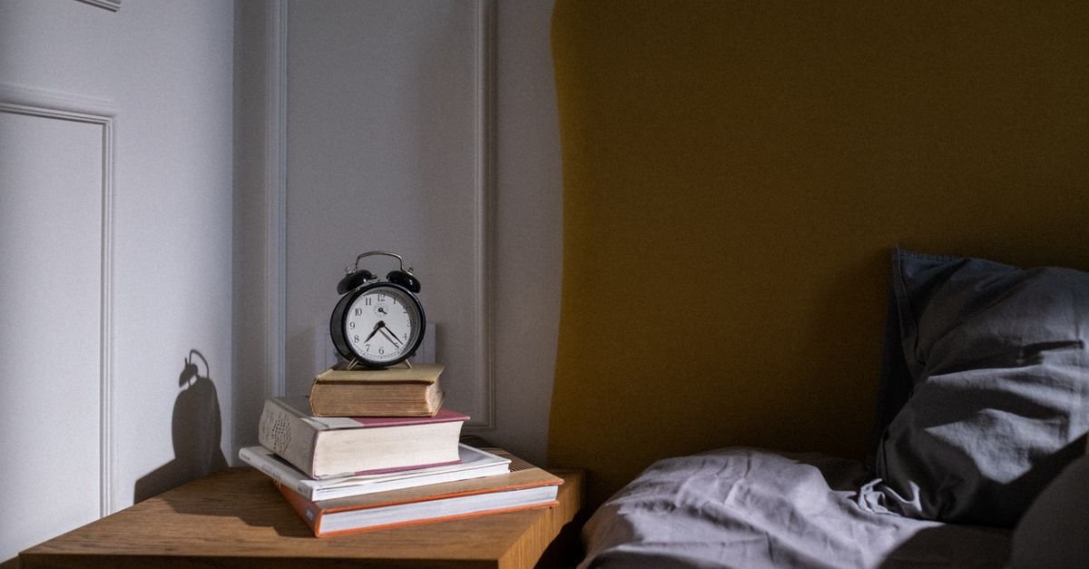 An alarm clock standing on a stack of books on a nightstand