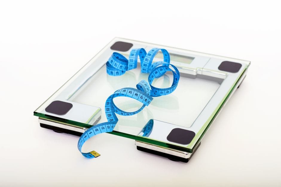 A glass smart scale with a blue measuring tape