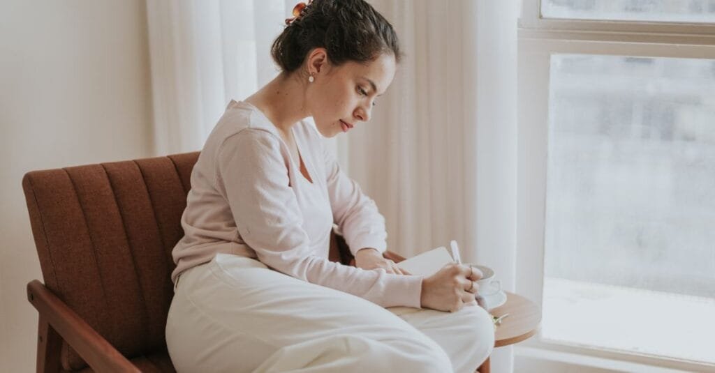 Woman journaling by a sunlit window