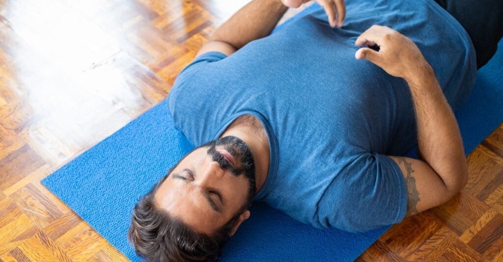 Man practicing relaxation breathing on a mat