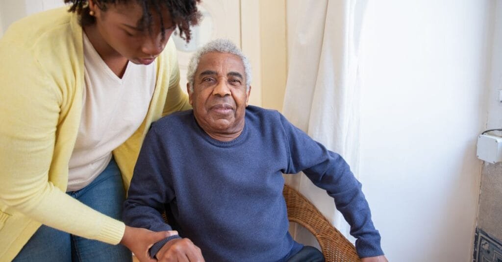 A woman assisting an elderly man at home